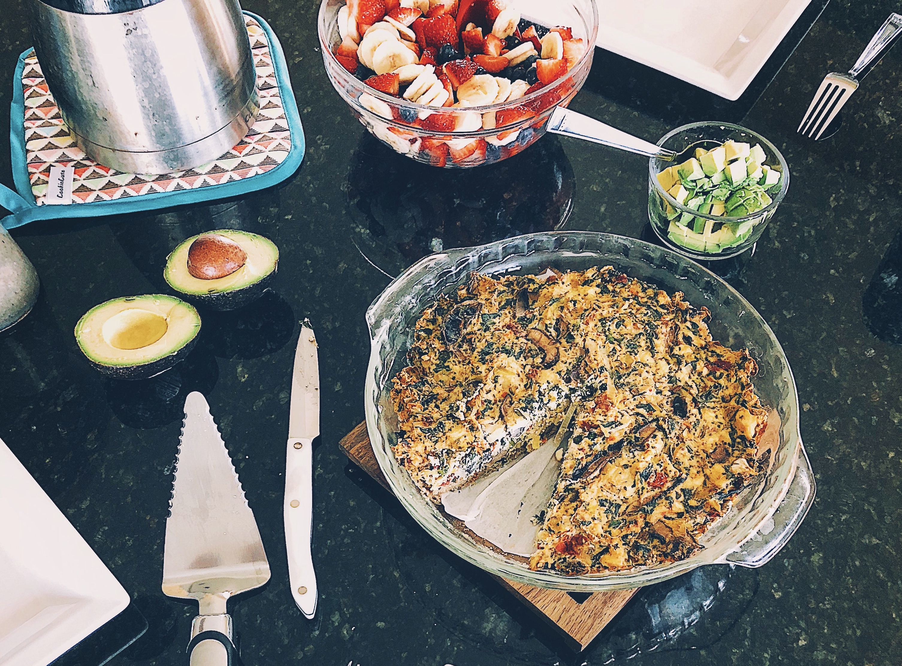vegan tofu quiche in pie pan on kitchen counter with fresh fruit and avocado