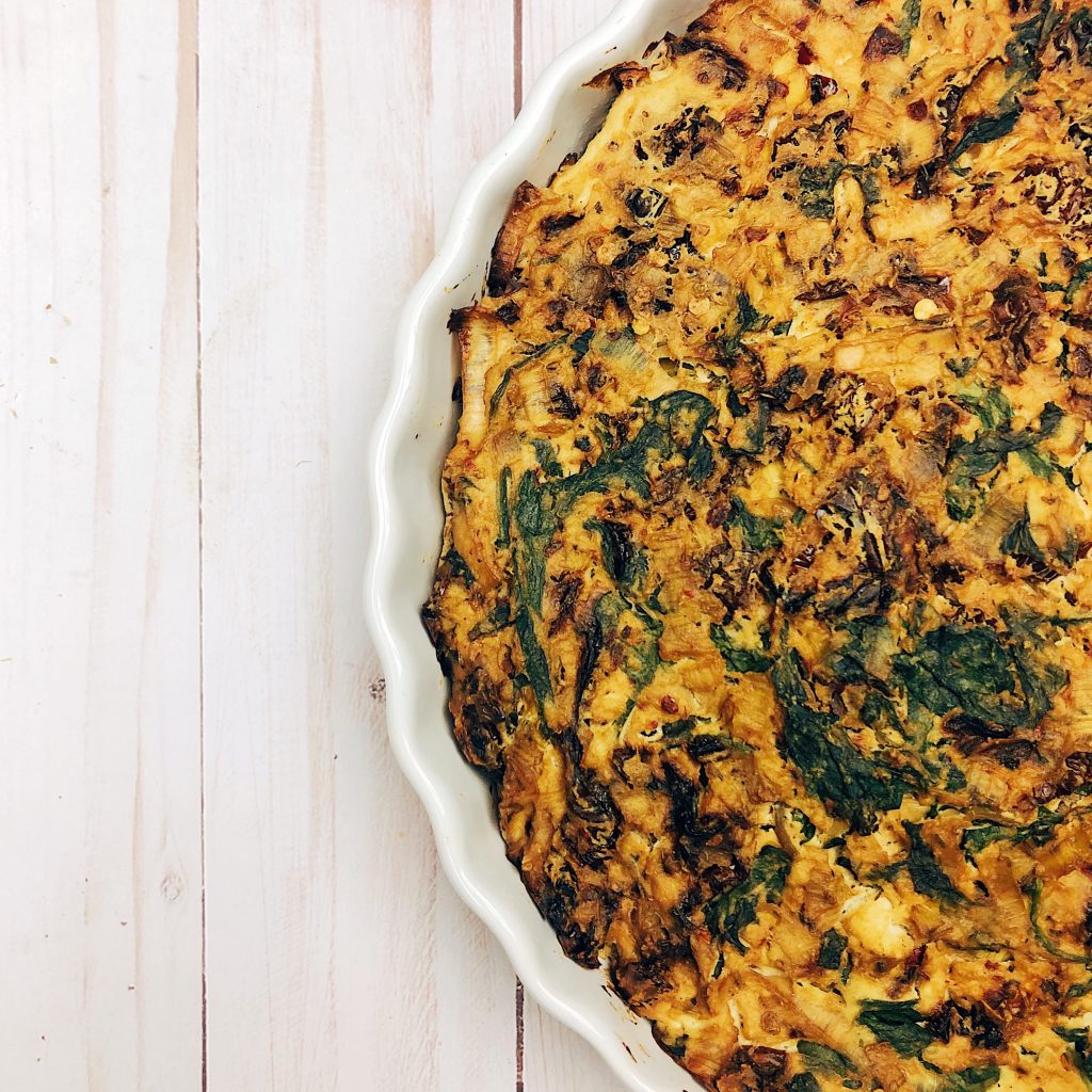 tofu quiche with sun-dried tomatoes and spinach in white pie container